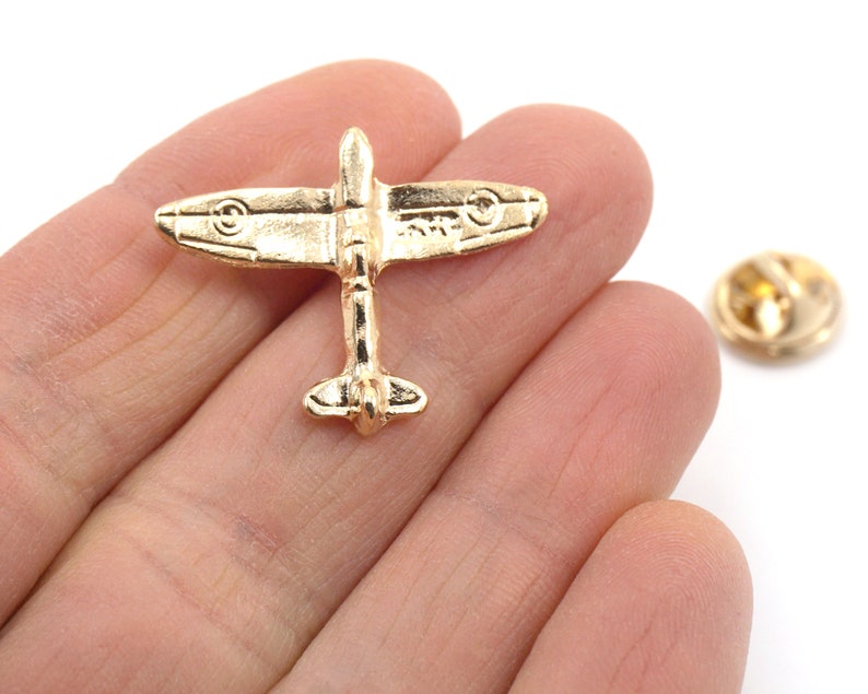 Puede incluir: Pin de metal dorado de un avi&oacute;n vintage. El pin tiene un cierre de seguridad en la parte posterior.