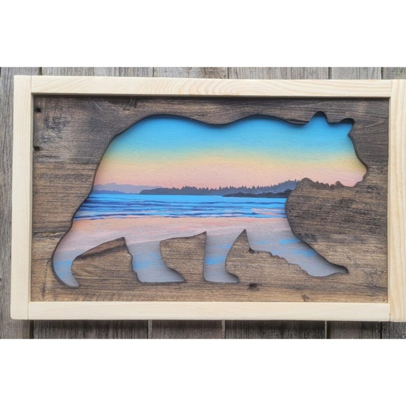 May include: A wooden wall art piece featuring a silhouette of a bear with a sunset beach scene visible through the cutout. The bear is facing right and the scene is a beach with a line of trees in the distance.