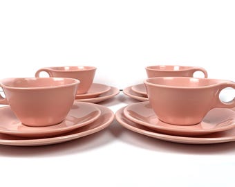 Puede incluir: Juego de cuatro tazas de té y platillos rosas. Cada taza y platillo está hecho de un material liso y brillante.