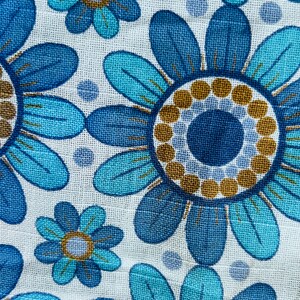 May include: Blue and turquoise floral fabric with a repeating pattern of stylized flowers. The flowers have a blue center with a brown ring around it.