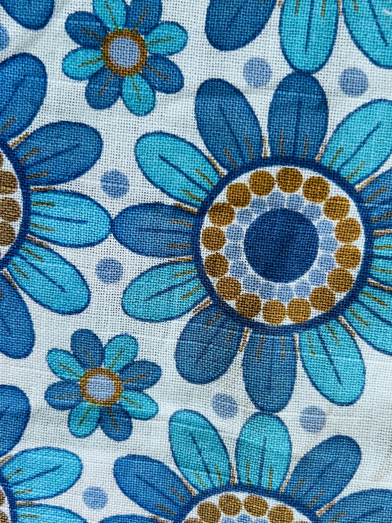 May include: Blue and turquoise floral fabric with a repeating pattern of stylized flowers. The flowers have a blue center with a brown ring around it.