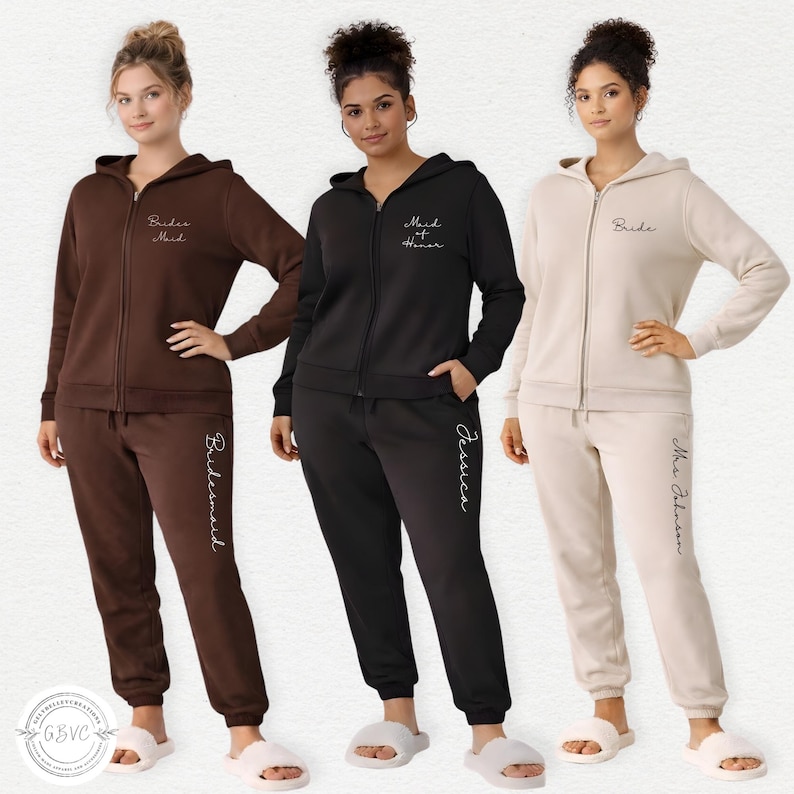 May include: Three women wearing matching zip-up hoodies and sweatpants in brown, black, and beige. The outfits have text including "Bride", "Bridesmaid", "Maid of Honor", and a name. The outfits are part of a bridal party collection.