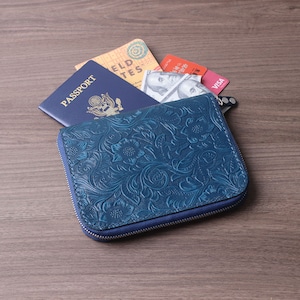 Bolsa para passaporte de couro azul em relevo com vários compartimentos para cartões, zíper seguro e compartimento AirTag para assuntos comerciais e viajantes.