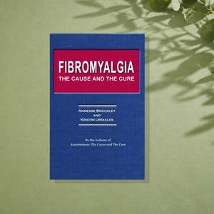 May include: A blue book titled Fibromyalgia: The Cause and The Cure by Annesse Brockley and Kristin Undiales. The cover features a red rectangular inset with white text and additional white text below, including the phrase By the Authors of Autoimmune: The Cause and The Cure.