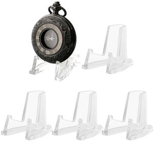May include: Set of 6 clear plastic display stands for pocket watches. The stands are designed to hold the watch upright and are perfect for displaying a collection of pocket watches.