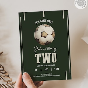 Puede incluir: Una invitación de cumpleaños verde y blanca con temática de fútbol para un niño que cumple dos años. La invitación presenta un balón de fútbol de estilo vintage, el texto "¡Es hora de jugar!" y "Jake cumple DOS". La invitación también incluye la fecha, la hora y el lugar de la fiesta.