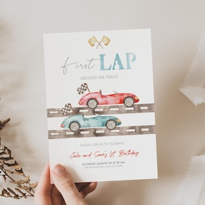 May include: A white invitation card with a watercolor illustration of two race cars on a track. The text on the card reads "first LAP around the track" and "Please join us to celebrate Jake and Sami's 1st Birthday".