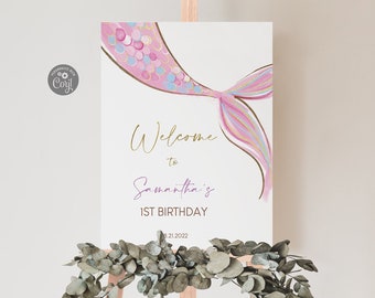 May include: A white welcome sign with a pink and gold mermaid tail illustration. The text reads "Welcome to Samantha's 1st Birthday 8.21.2022".