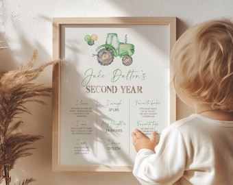May include: A green and yellow tractor illustration with balloons on a white background. The text "Jake Dalton's Second Year" is written in brown and green. The text below lists the child's age, weight, height, and favorite things.