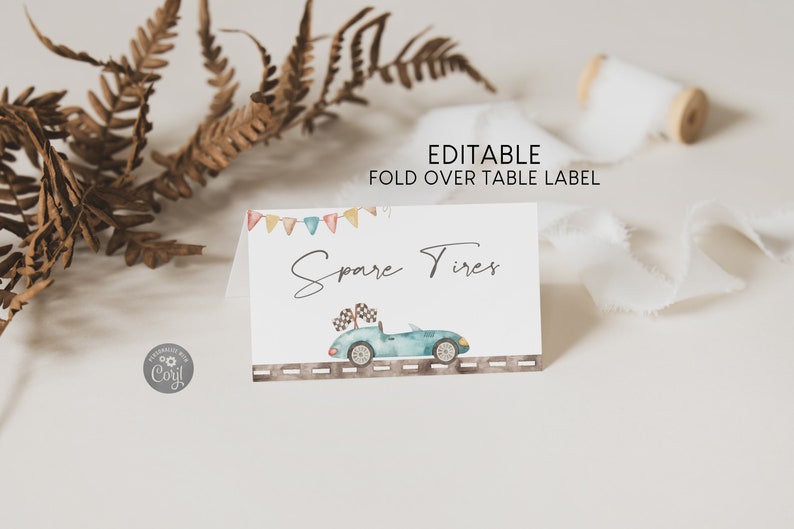 May include: Editable fold over table label with a blue car and the text "Spare Tires" in a handwritten font. The label has a colorful banner at the top and a gray road with white lines at the bottom.