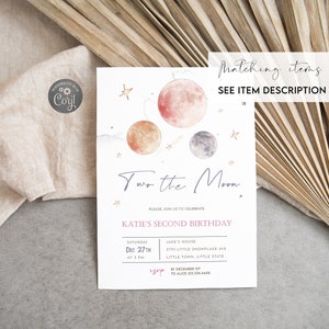 May include: A white invitation card with a watercolor illustration of planets and stars. The text reads "Two the Moon" and "Katie's Second Birthday". The invitation includes details for the birthday party, including the date, time, and location.