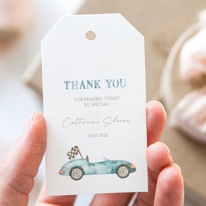 May include: A white thank you tag with blue text that reads "Thank You for making today so special! Catherine's Shower 06.25.2022". A blue watercolor car with a checkered flag is illustrated on the tag.