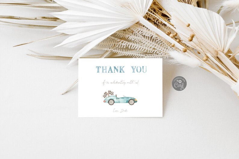 May include: A white thank you card with blue text that says "Thank You for celebrating with us."  A blue and green cartoon car with a checkered flag on top is in the center of the card. The text "Love, Jake" is at the bottom of the card.