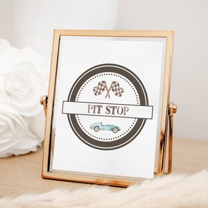 May include: A gold-framed sign with a black and white checkered flag design and the text "PIT STOP". The sign features a vintage race car and is perfect for a racing-themed party.