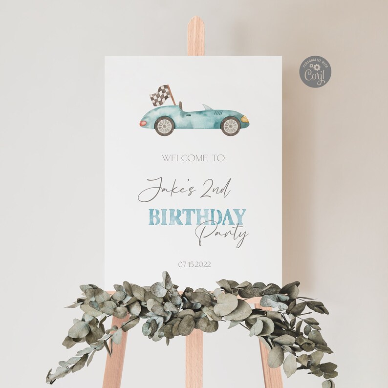 May include: A blue and white welcome sign for a birthday party. The sign features a watercolor illustration of a blue race car with a checkered flag. The text on the sign reads "Welcome to Jake's 2nd Birthday Party 07.15.2022".