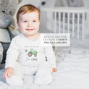 May include: A baby boy wearing a white onesie with a green tractor and the text "Start your tractor I'm one" printed on it. The baby is sitting on a white bed with a gray teddy bear beside him.