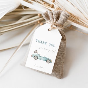 May include: A white thank you tag with blue text that says "Thank you for racing by!" and a watercolor illustration of a blue race car with a checkered flag. The tag is attached to a small burlap bag.