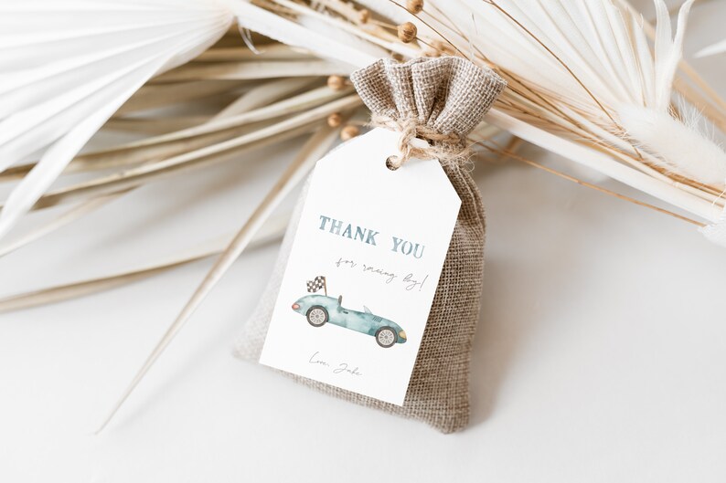 May include: A white thank you tag with blue text that says "Thank you for racing by!" and a watercolor illustration of a blue race car with a checkered flag. The tag is attached to a small burlap bag.