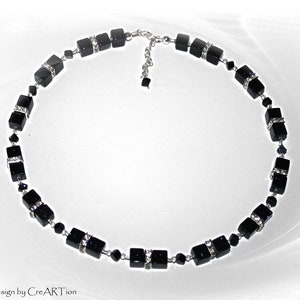 May include: A black cube bead necklace with silver accents and small clear crystals. The necklace has a silver chain and clasp. The design is by CreARTion.