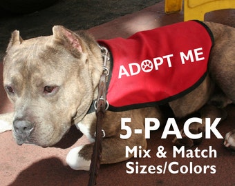 May include: A brown and white pit bull wearing a red vest with the text "ADOPT ME" and a paw print. The vest has a black trim. The dog is wearing a black leather leash. The text "5-PACK Mix & Match Sizes/Colors" is below the dog.
