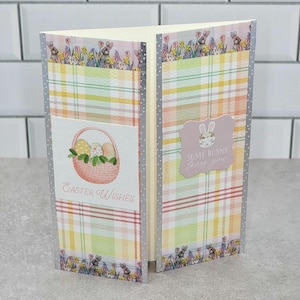 May include: A pink and white plaid card with a bunny and basket of eggs. The card says "Easter Wishes" and "Some bunny loves you".