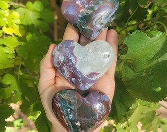 May include: Three heart-shaped polished stones with a green, brown, and purple agate pattern.