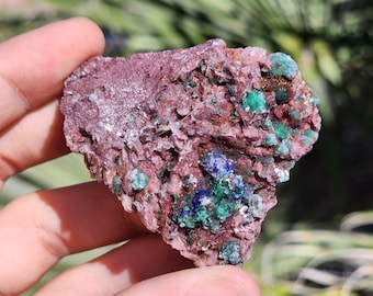 May include: A rough, pink, and white rock with green and blue crystals. The rock is a mix of minerals, including malachite, azurite, and calcite.