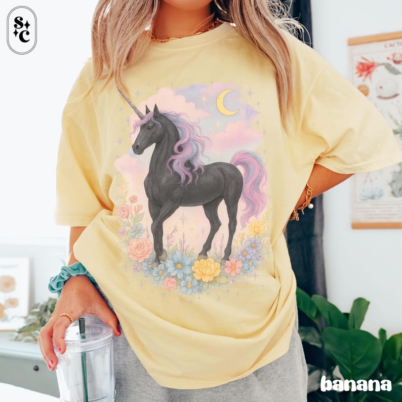Peut inclure: T-shirt jaune clair avec un motif de licorne noire, crini&egrave;re et queue violettes et roses, entour&eacute;e de fleurs, de nuages et d'un croissant de lune. Le mot "banana" est imprim&eacute; en bas &agrave; droite. Manches courtes.