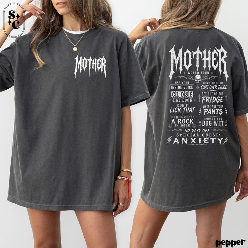 May include: A charcoal gray short-sleeve t-shirt featuring the word MOTHER in a white gothic font on the front chest. The back displays the same MOTHER text above a list of phrases including USE YOUR INSIDE VOICE, CLOSE THE DOOR, and ANXIETY.