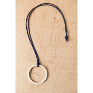 May include: A simple wooden circle pendant necklace with a dark blue cord.