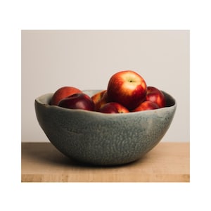 May include: A blue ceramic bowl filled with red apples. The bowl has a textured surface and a wide rim.