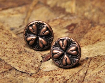 May include: A pair of copper-colored earrings with a four-leaf clover design.
