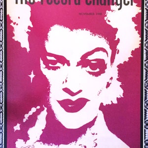 May include: A vintage poster for "The Record Changer" magazine, featuring a white silhouette of a woman's face with a dramatic hairstyle against a bright pink background. The text "The Record Changer" is in black lettering at the top of the poster, and "November 1948" is in smaller black lettering below.
