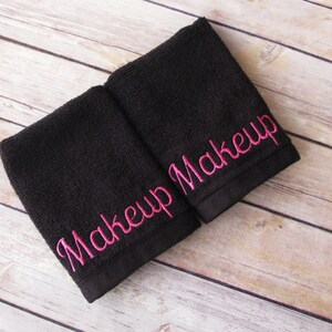 May include: Two black washcloths with pink embroidery that reads "Makeup Makeup".