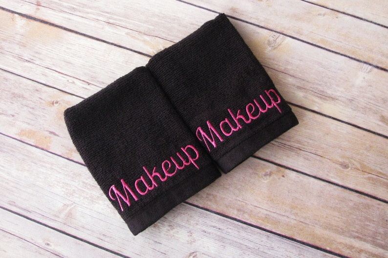 May include: Two black washcloths with pink embroidery that reads "Makeup Makeup".