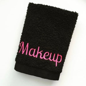 May include: Black makeup remover towel with pink embroidery that says "Makeup".