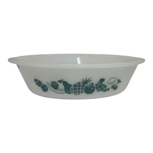 May include: A white glass bowl with a wide rim and a tapered base. The exterior features a repeating dark green graphic print of various fruits, including strawberries, a pear, a pineapple, an apple, grapes, and cherries arranged in a horizontal row.