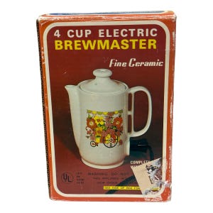 Puede incluir: Una caja de cartón rectangular para una cafetera eléctrica de 4 tazas Brewmaster, con una jarra de cerámica blanca y un gráfico de carro floral. La caja es principalmente naranja y marrón con texto en blanco y detalles técnicos.