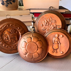 May include: A white ceramic mug with a black handle and the text "But First, Coffee" in a handwritten style. The mug is on a white surface. The mug is approximately 4 inches tall.