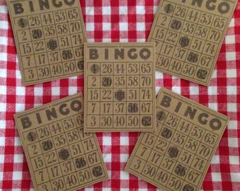 May include: Five rectangular tan bingo cards with dark brown grid lines and numbers. Each card features the word BINGO at the top, five rows of numbers, and a central FREE space. The cards are arranged in a cluster on a red and white checkered surface.