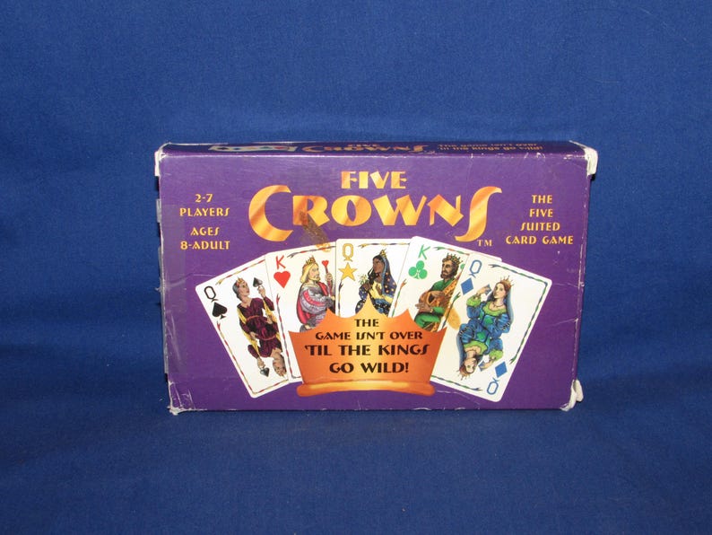 May include: A purple Five Crowns card game box with gold lettering and card illustrations. The box reads "Five Crowns" and "The Five Suited Card Game". The game is for 2-7 players, ages 8-adult. The text "The game isn't over 'til the kings go wild!" is also visible.
