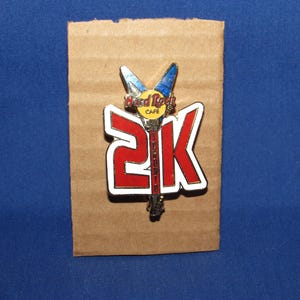 May include: A red and white enamel pin with a guitar and the text "Hard Rock Cafe" and "2K Toronto".