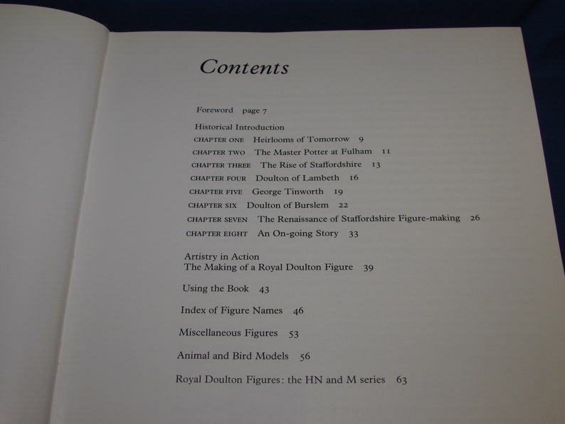 May include: A book titled "Royal Doulton Figures" with a table of contents listing chapters on the history of the company, including the rise of Staffordshire, Doulton of Lambeth, and the Renaissance of Staffordshire figure-making. The book also includes sections on artistry in action, using the book, and an index of figure names.