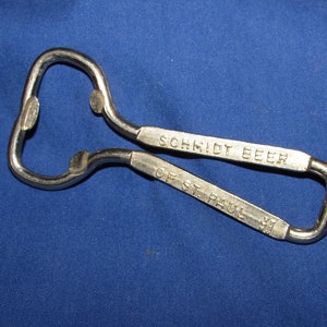 May include: A silver bottle opener with the words "Schmidt Beer of St. Paul, MN" engraved on it.