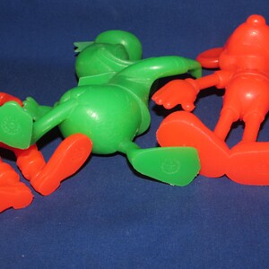 May include: Three plastic cartoon character figurines. One is green, one is red, and one is red and white. The figurines are posed in a playful manner.