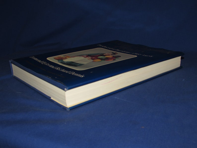 May include: A blue hardcover book with the title "The Collector's Encyclopedia of Dolls" and the author "Dolores Elizabeth and Richard Dennis". The cover features a colorful illustration of a doll holding a basket of fruit.