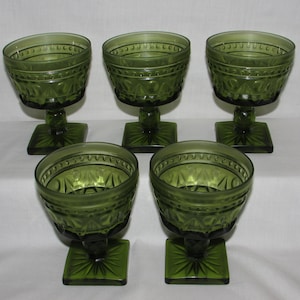 May include: Set of five green glass goblets with a square base and a diamond pattern.