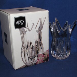 May include: A clear Mikasa crystal vase with a tulip-like design, next to its original box. The vase has a textured, fluted body and a flared, petal-shaped rim. The box features the Mikasa logo.