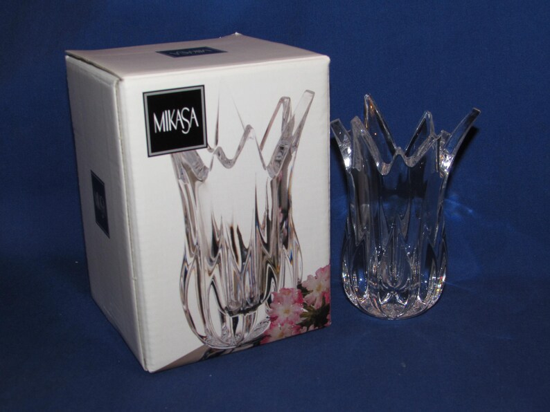 May include: A clear Mikasa crystal vase with a tulip-like design, next to its original box. The vase has a textured, fluted body and a flared, petal-shaped rim. The box features the Mikasa logo.