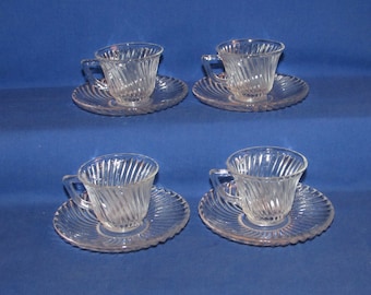 May include: Set of four clear glass teacups and saucers with a swirl design. The cups and saucers are all the same size and shape.